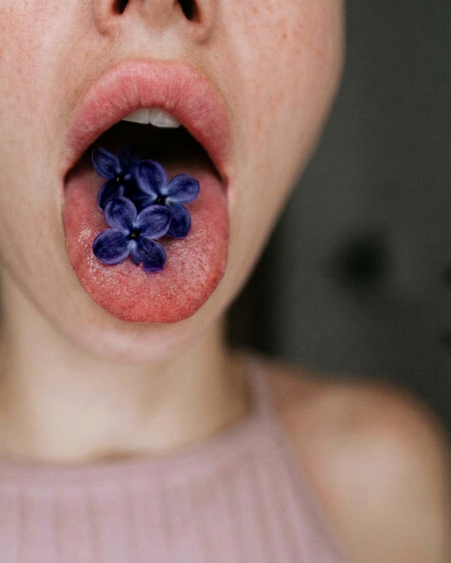 close up shot of a woman with lilac flowers on her tongue